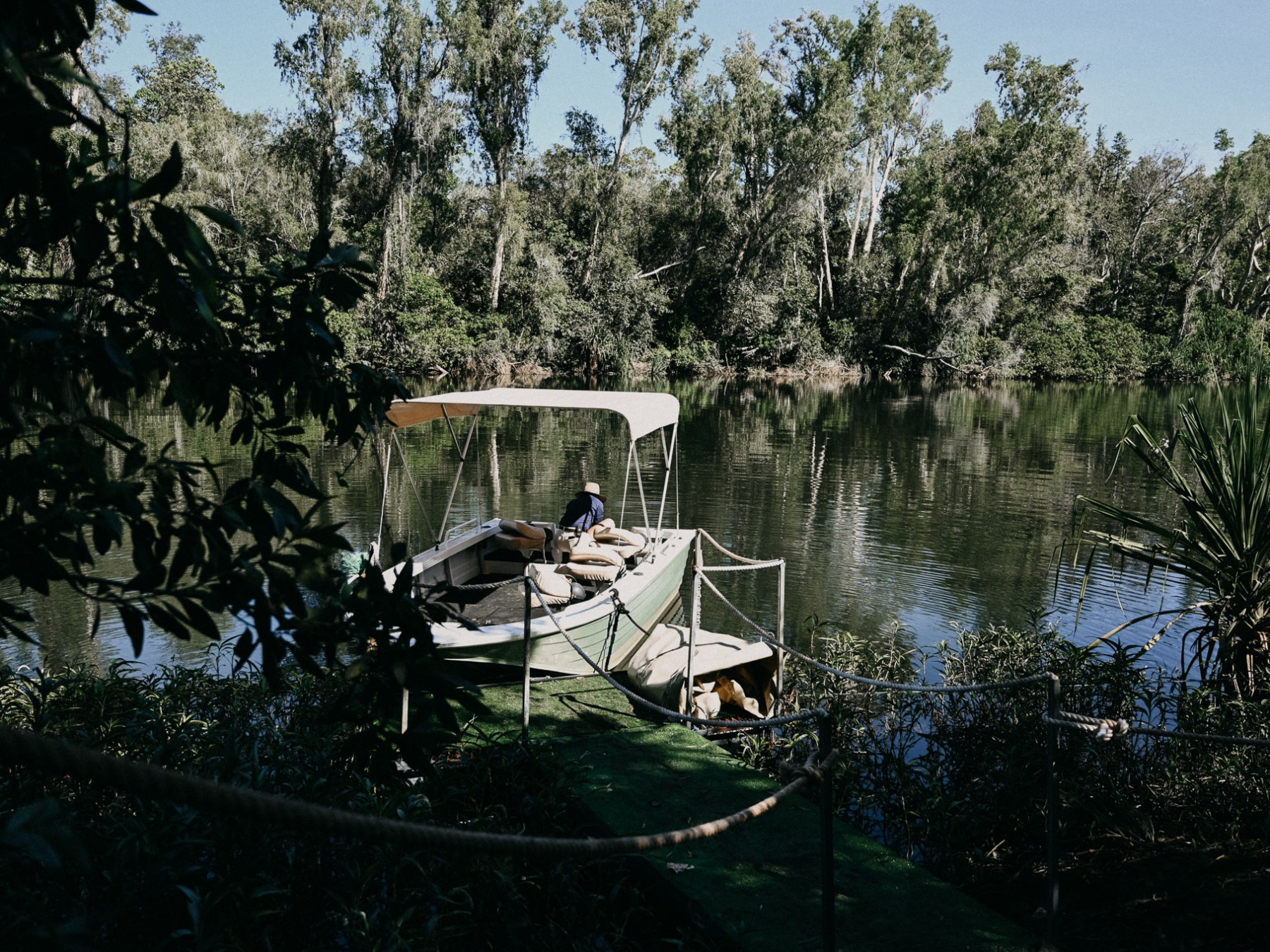 Small boat docked on a river, surrounded by trees.